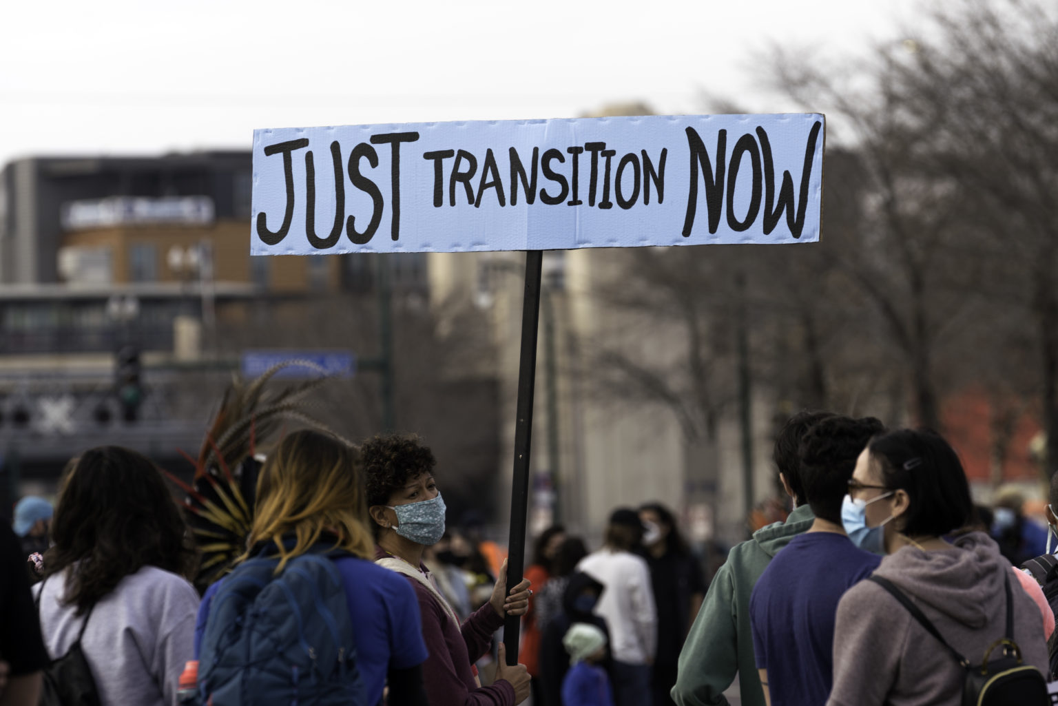 A_woman_holds_a_Just_Transition_Now_sign_at_a_rally_in_Minneapolis,_Minnesota_(50577736571)